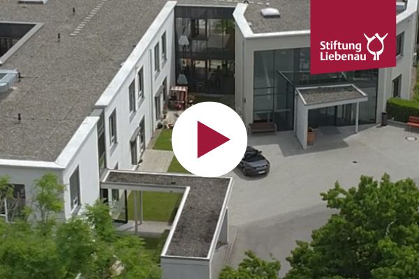 Eine Luftaufnahme vom Haus und ein Playbutton in der Mitte des Bilds.