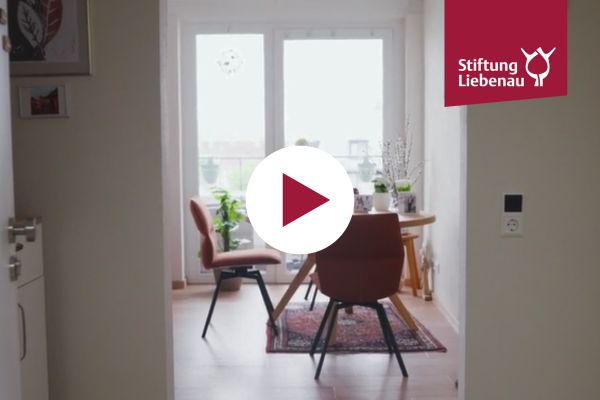 Eine Innenaufnahme vom Haus und ein Playbutton in der Mitte des Bilds.