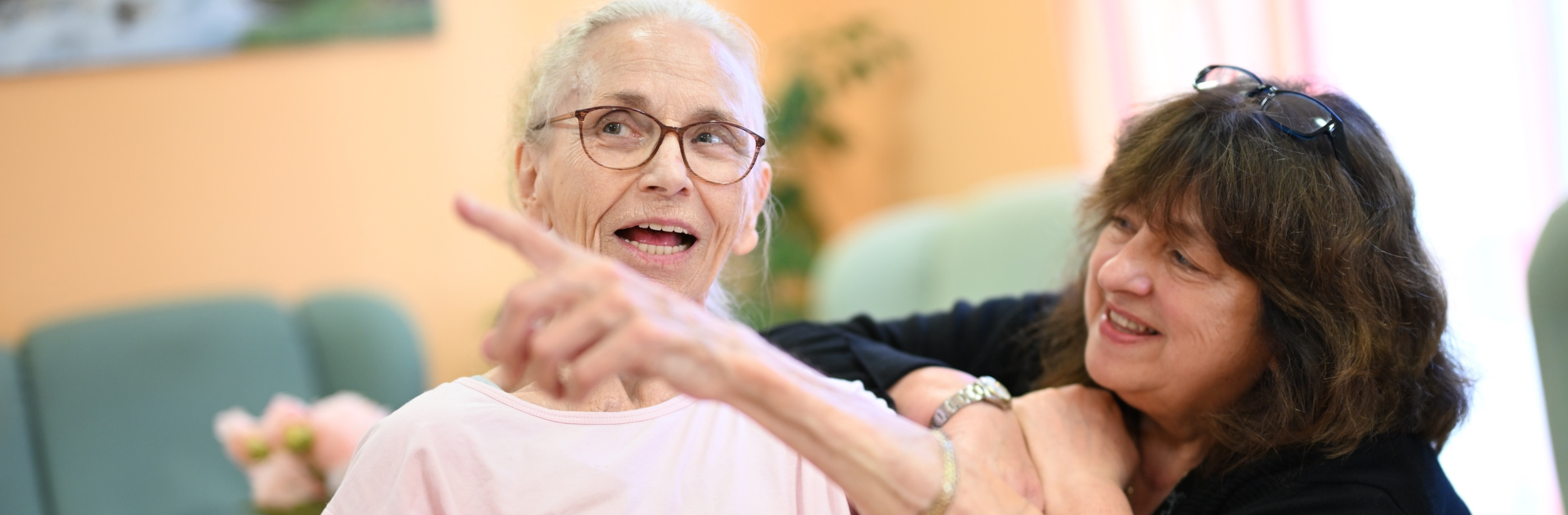 Das Bild zeigt eine ältere Dame mit einer Pflegerin
