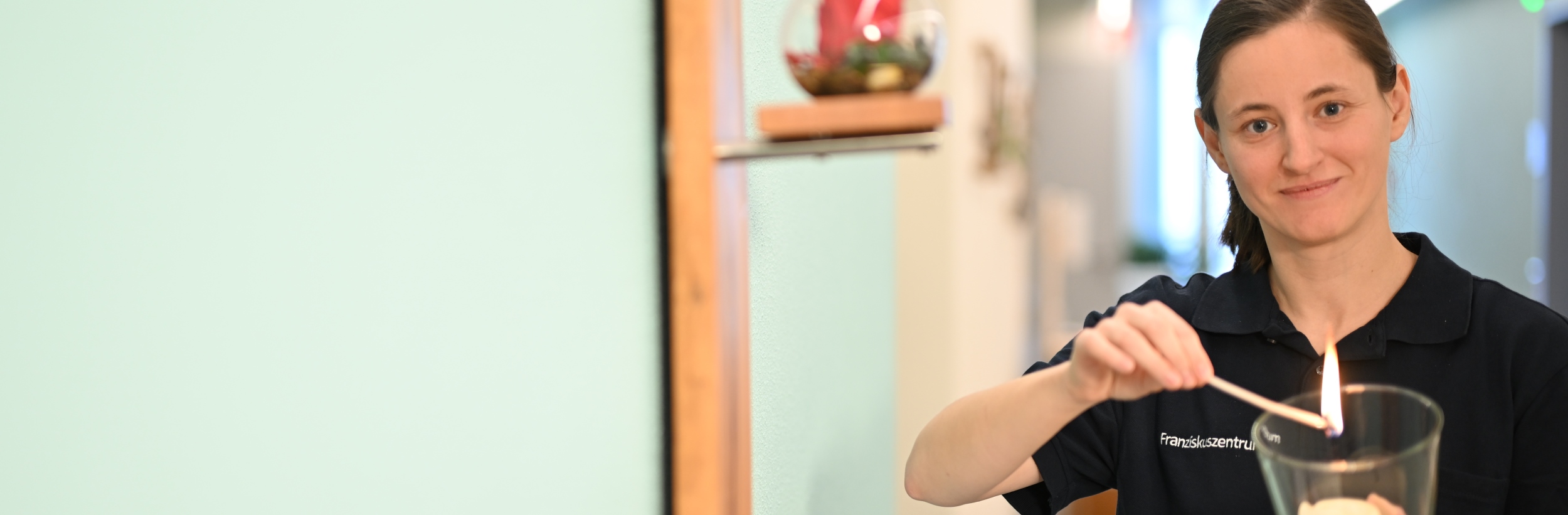 Das Bild zeigt eine junge Frau beim Entzünden einer Kerze