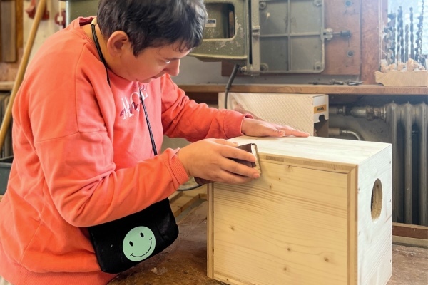 Besuch einer Zimmerei Das Bild zeigt eine Frau, die eine Fühlbox schleift