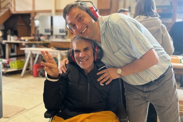 Besuch einer Zimmerei Das Bild zeigt zwei Männer mit Gehörschutz, einer davon im Rollstuhl