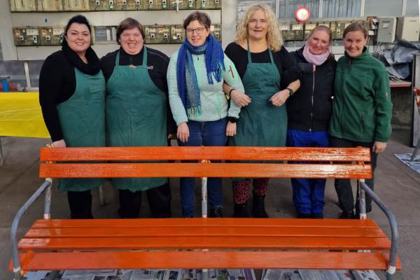 Das Bild zeigt die Frauenbeauftragten der Liebenauer Arbeitswelten vor einer orange gestrichenen Bank