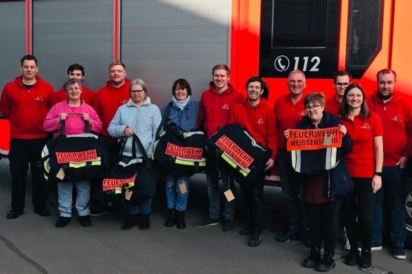 : Zehn Angehörige der Freiwilligen Feuerwehr Weißensberg holen die aus Ausrüstung hergestellten Taschen beim Liebenauer Nähwerk in Meckenbeuren ab. Dort freut man sich über den außergewöhnlichen Besuch.