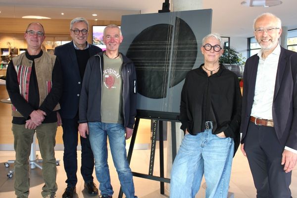 Gruppenfoto mit Team und Gästen Auf dem Bild sind fünf Personen vor einem Ausstellungstück zu sehen. Vier Männer und eine Frau, die alle in die Kamera schauen und lächeln.