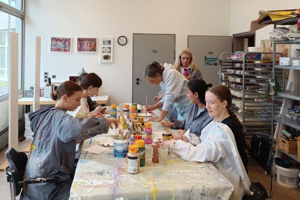 Gemeinsames Malen Das Bild zeigt eine Gruppe von Mädchen die einen Malerkittel tragen und gemeinsam an einem Bild malen