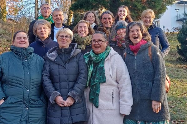 Das Bild zeigt eine Gruppe von Personen, die alle in einem Wald stehen und in die Kamera lächeln.