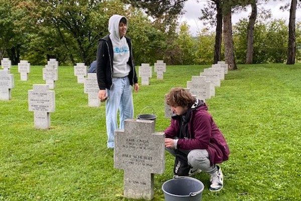 Grabpflege Zwei Jugendliche reinigen Gräber.