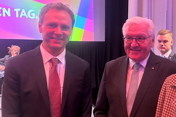 Bundespräsident Zwei Männer im Anzug stehen nebeneinander und schauen in die Kamera.