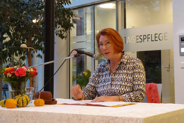 Petra Frey Petra Frey sitzt an einem Tisch und spricht in ein Mikrophon.