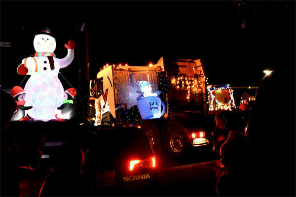 Nikolausfahrt Ein großer leuchtender Schneemann und LKWs mit Lichterketten.