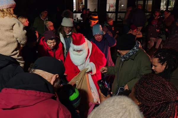 Nikolausfahrt Ein Nikolaus verteilt Geschenke und viele Personen stehen dabei.
