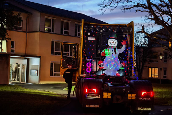 Nikolausfahrt Ein beleuchteter Schneemann im Anhänger eines LKWs vor einem Haus.