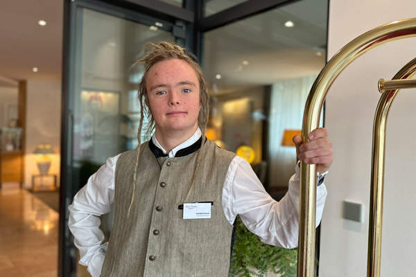 Ein Mann mit einer Weste steht im Eingangsbereich eines Hotels.