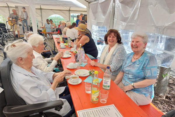Mehrere Personen sitzen an einem Tisch in einem Festzelt.