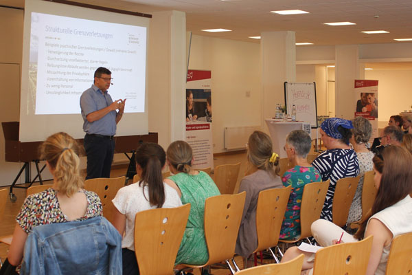 Ein Mann bei einem Vortrag mit vielen Zuhörerinnen und Zuhören.