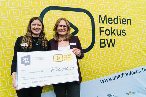 Förderpreis Zwei Frauen halten einen Scheck und lächeln in die Kamera.