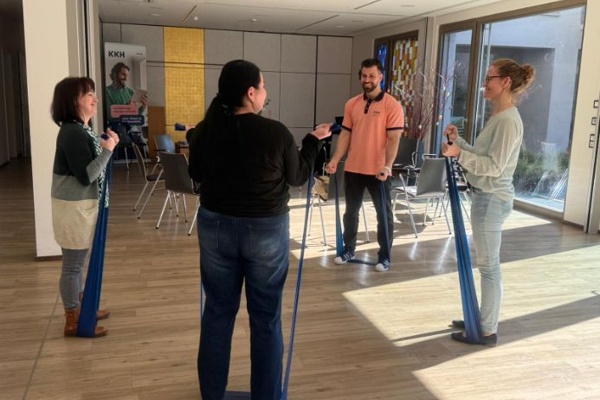 Übungen am Gesundheitstag Vier Personen trainieren mit Bändern.