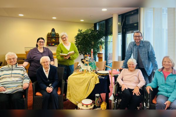 Bewohnern des Heims werden Märchen vorgetragen Eine Personengruppe lächelt in die Kamera