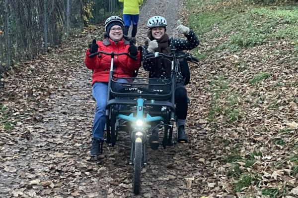 Zwei Damen sitzen in einem Doppelsitzer- Dreirad
