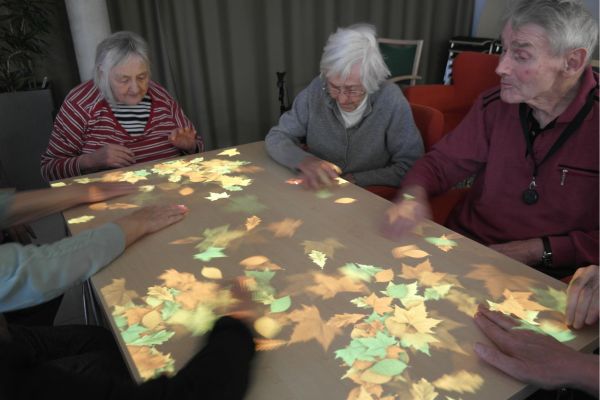 Tovertafel Eine Gruppe älterer Menschen sitzt um einen anprojizierten Tisch