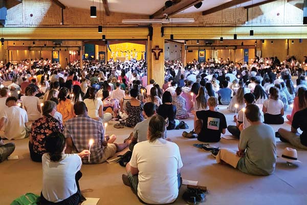 Taizé Ein Raum mit vielen sitzenden Personen und Kerzen.