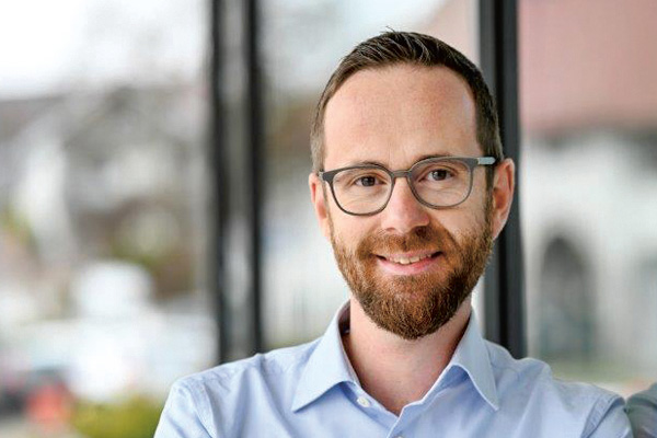 Ein Portraitfoto eines Manns, der in die Kamera lächelt.