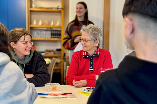 Das Foto zeigt mehrere Personen verschiedener Generationen im Gespräch.