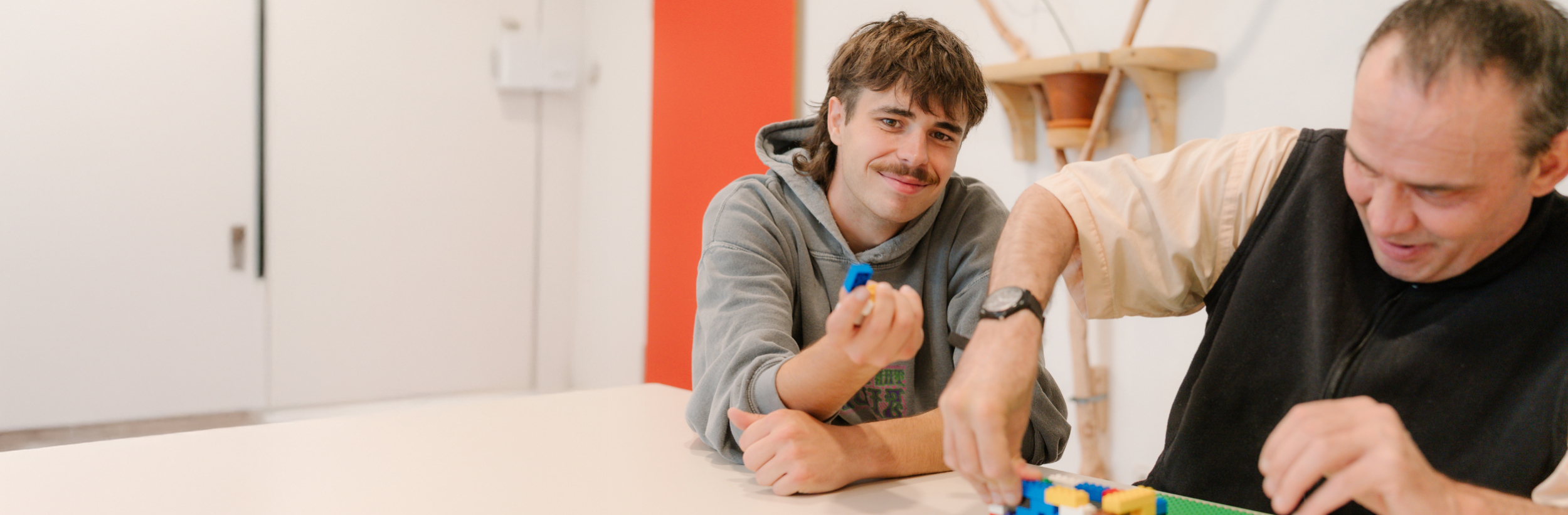 Das Bild zeigt zwei Männer an einem Tisch beim basteln