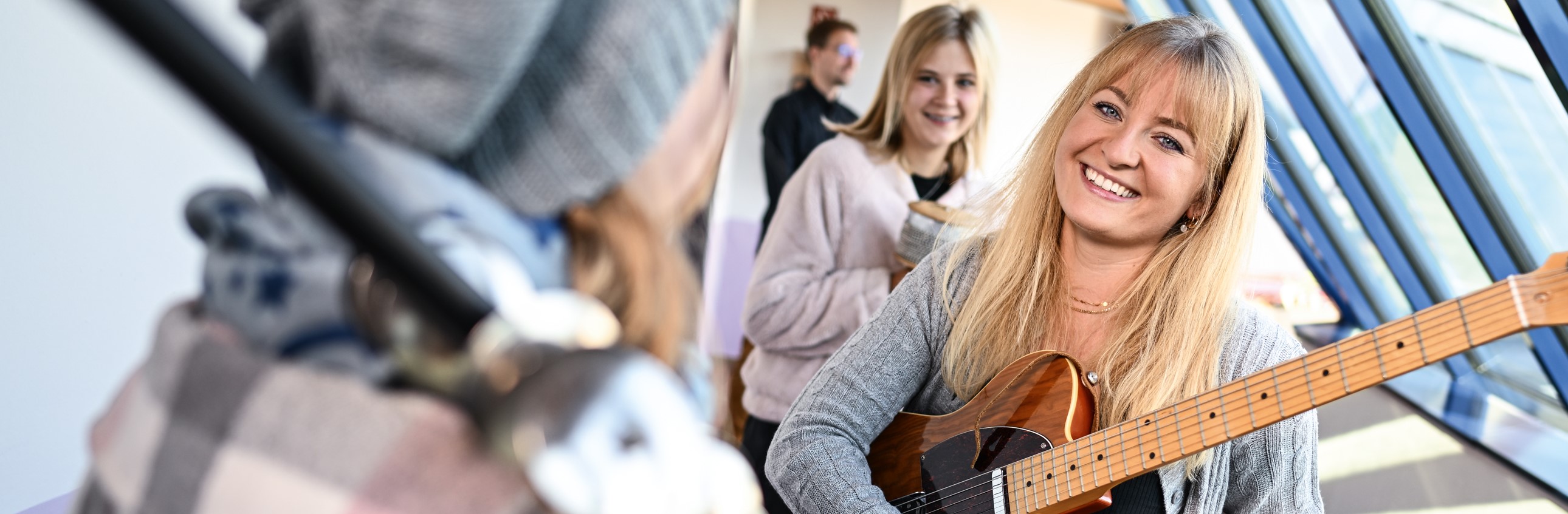 Das Bild zeigt eine junge Frau mit einer Gitarre in einer Gruppe Jugendlicher