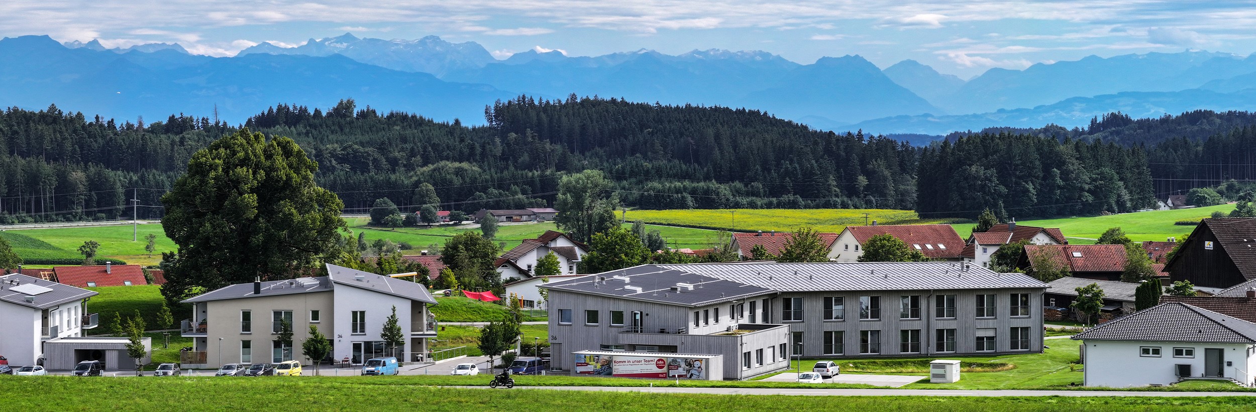 Das Bild zeigt eine Drohnenansicht des Hauses Magnus mit Alpenpanorama